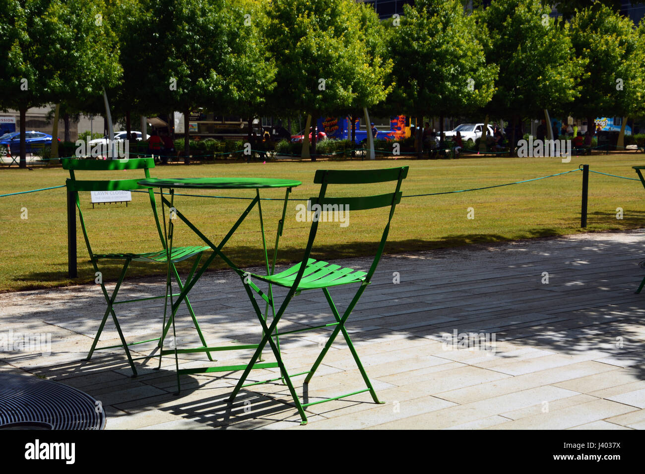 Öffentliche Tische und Stühle säumen die Wege und von Bäumen gesäumten Wege rund um Dallas' Downtown Klyde Warren Park auf einer vertieften Autobahn gebaut Stockfoto