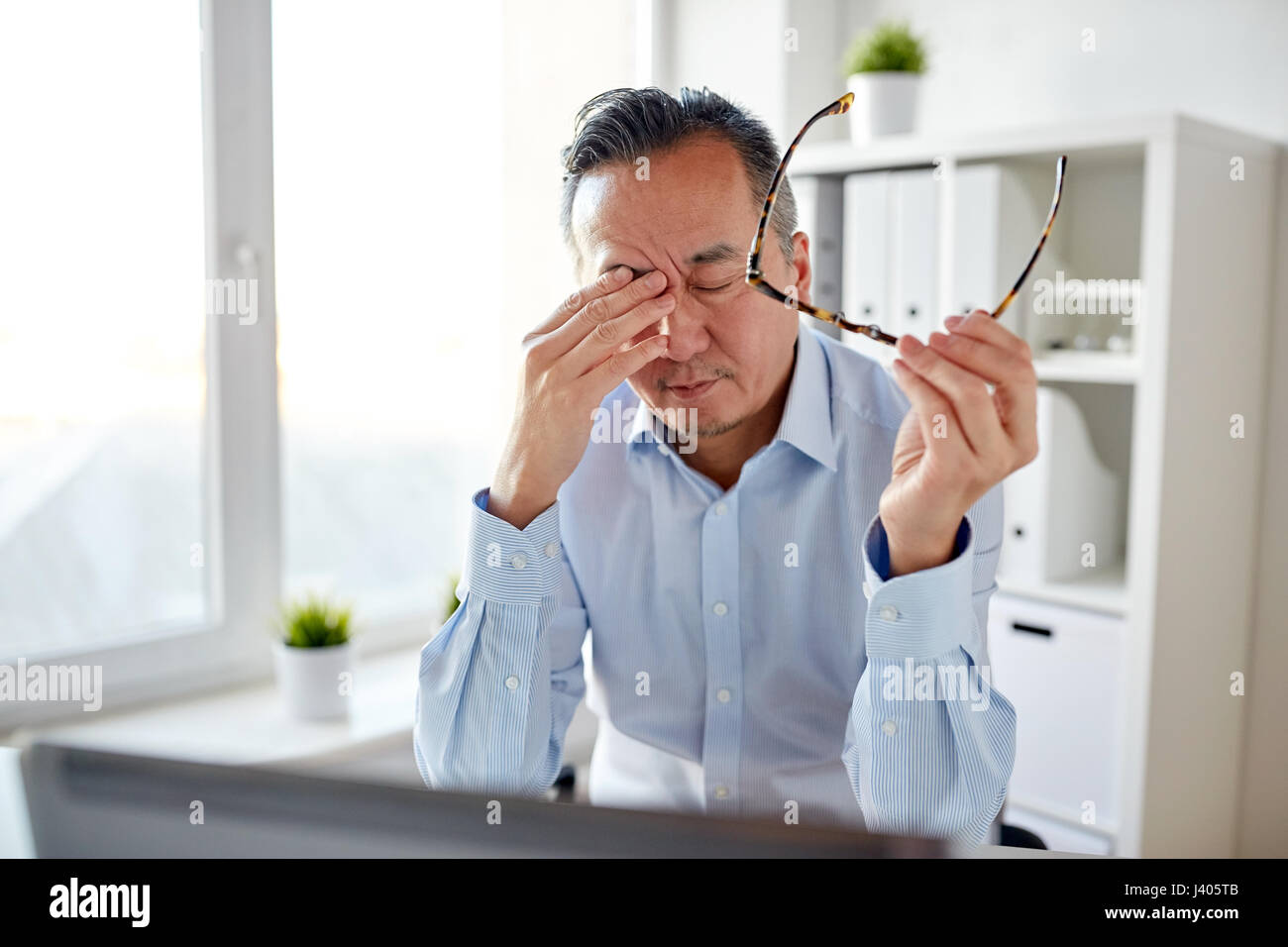 müde Geschäftsmann mit Brille am Laptop im Büro Stockfoto