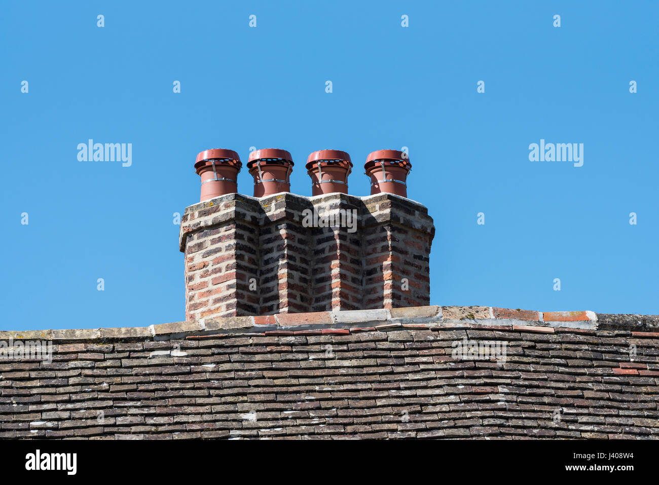Alte gemauerte Schornsteine mit modernen Tops. Stockfoto