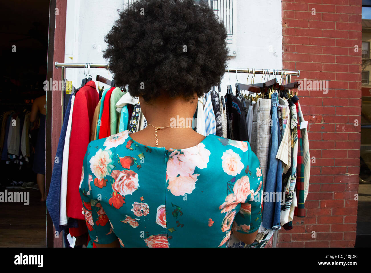 Rückansicht des jungen weiblichen Mode-Blogger mit Afro-Haar Blick auf Vintage Kleiderstange, New York, USA Stockfoto