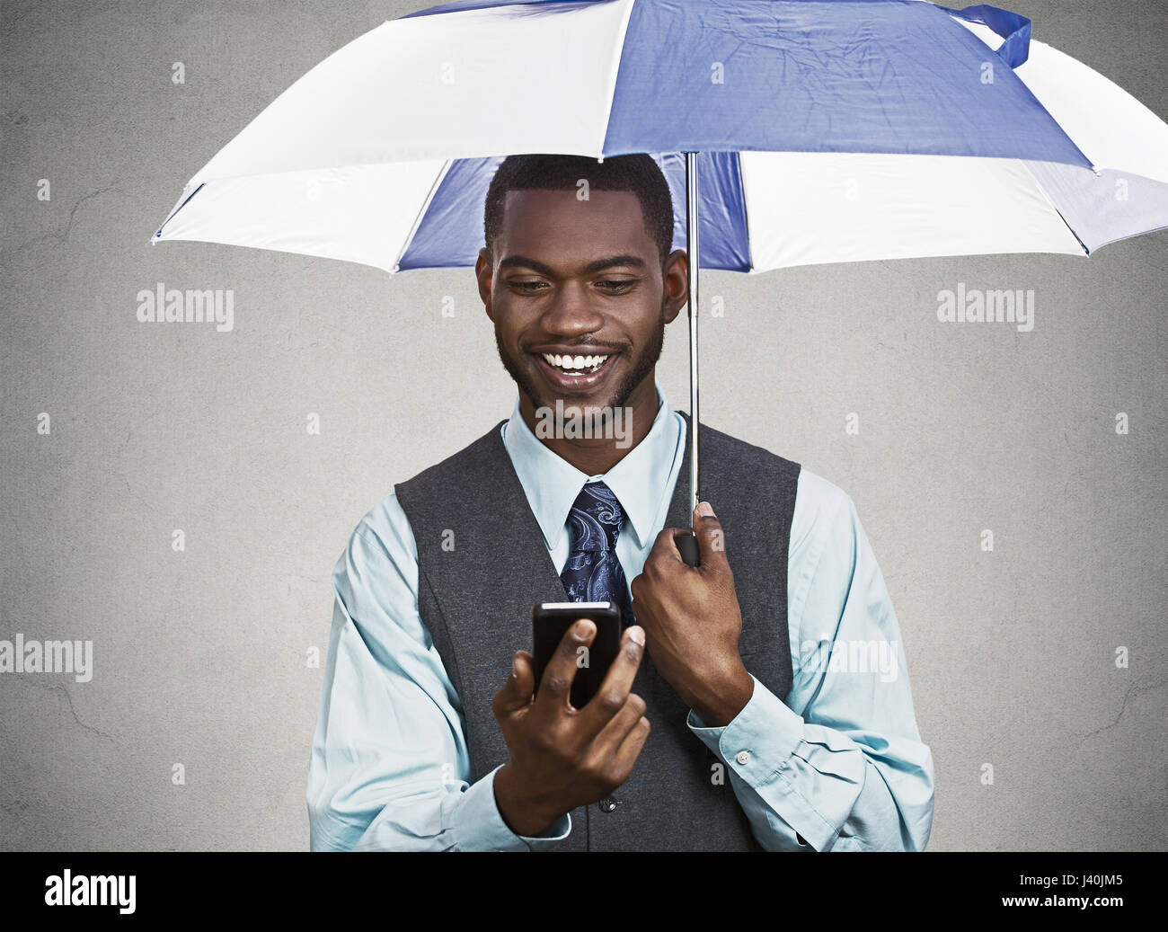 Closeup Portrait glücklich, Lächeln corporate Business-Mann, Executive lesen Nachricht Nachrichten auf Smartphone-Holding-Dach, geschützt vor Regen isoliert b Stockfoto
