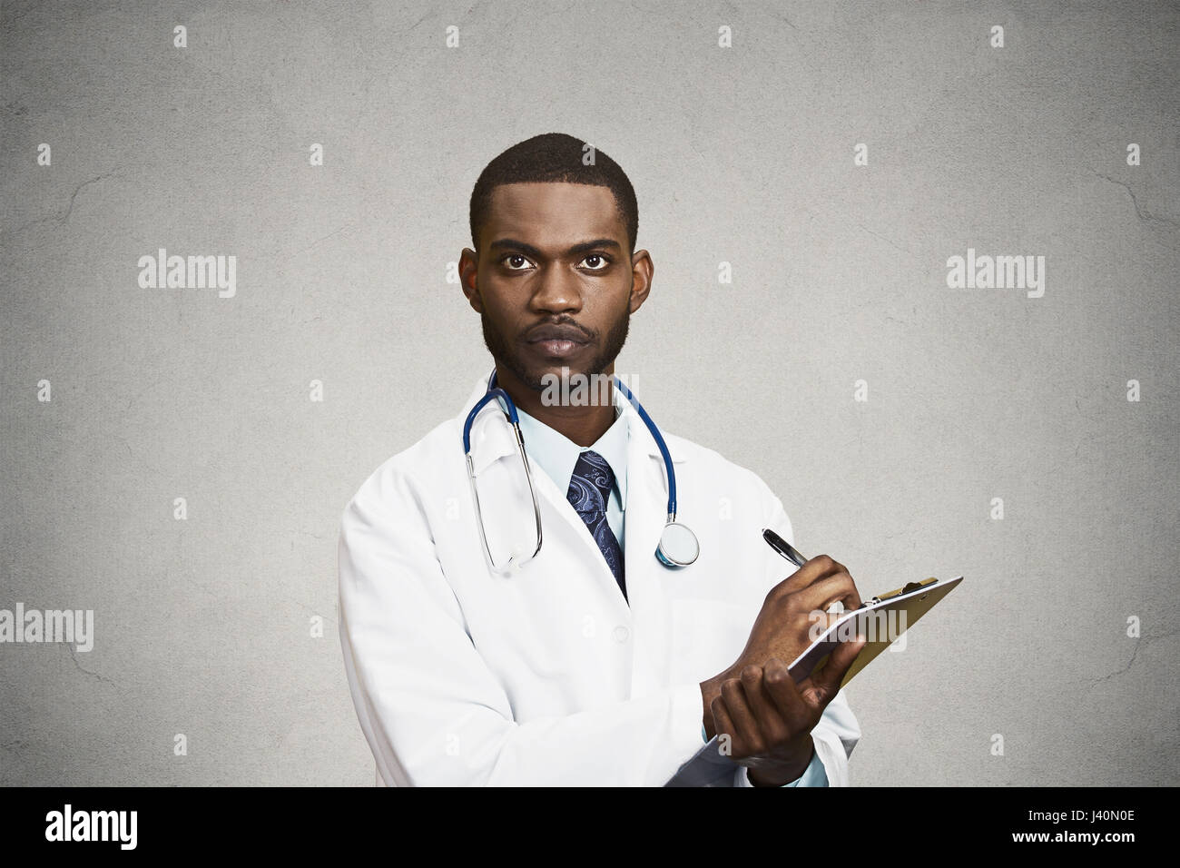 Closeup Portrait überzeugt junge männliche Hausarzt, Assistent Kardiologe, Gesundheitswesen professionelle Aufnahme Notizen aus Patienten isolierten schwarz, grau Stockfoto