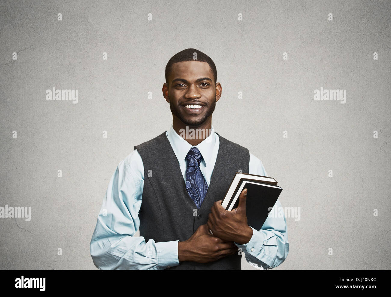Closeup junge intelligente, glücklich, gut aussehender Mann mit Büchern, bereit, bereit, seine Prüfung Test Finale, isoliert, schwarz, grau Hintergrund Ass lächelnd. Positive Stockfoto