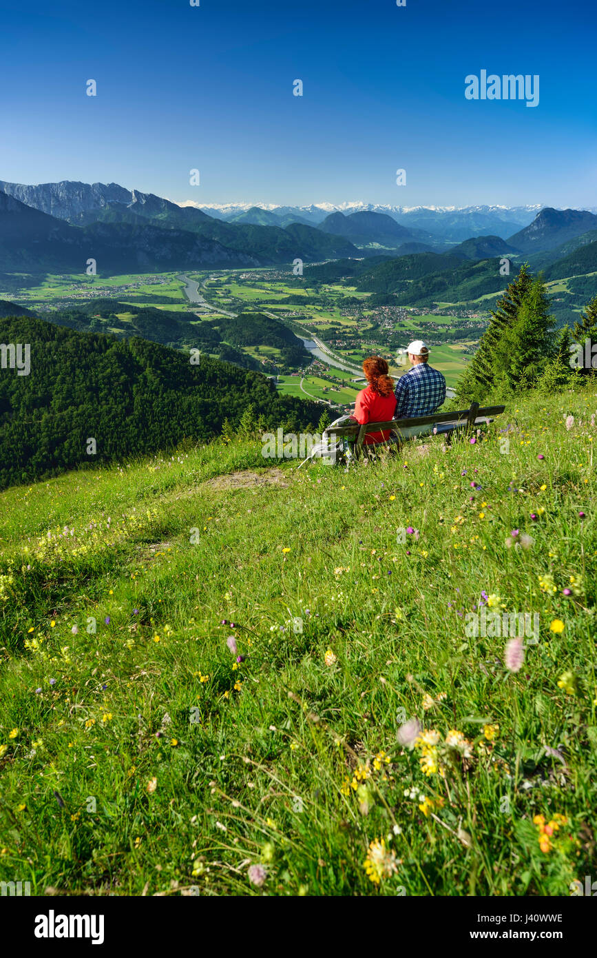 Zwei Personen sitzen auf einer Bank in Blumenwiese, Inntal im Hintergrund Kranzhorn, Chiemgauer Alpen, Tirol, Österreich Stockfoto