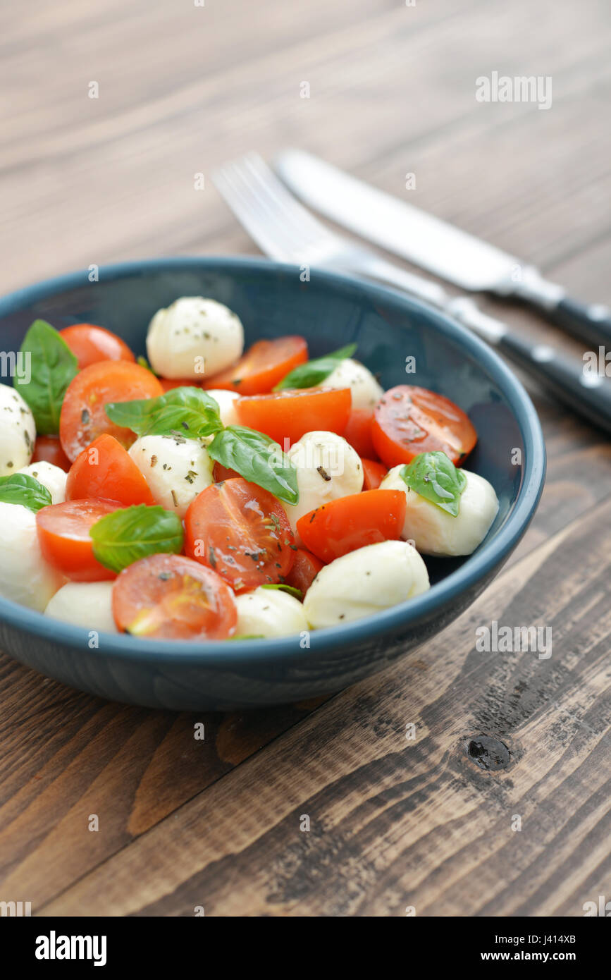 Caprese-Salat in Schüssel auf hölzernen Hintergrund Stockfoto
