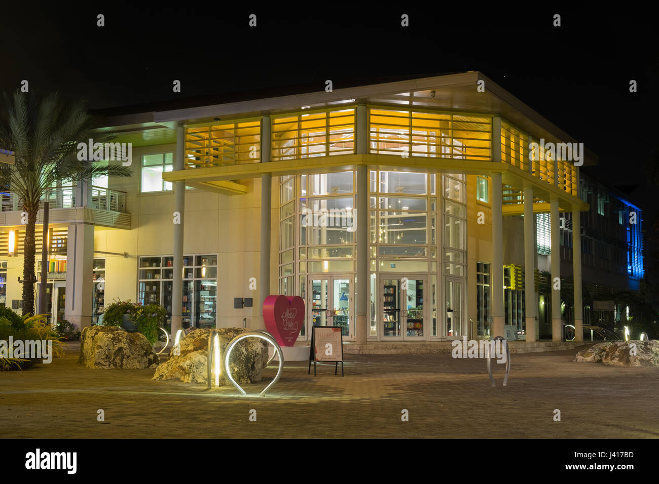 Moderne beleuchtete Glas-Buchhandlung Gebäude bei Nacht in einer Fußgängerzone der Camana Bay in der Karibik, Grand Cayman, Cayman Islands Stockfoto