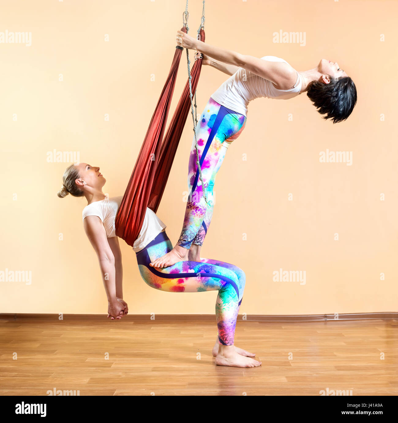 Zwei junge Frau beim Antigravity Yoga in Hängematte im Wellnessstudio mit leere Wand Hintergrund Stockfoto