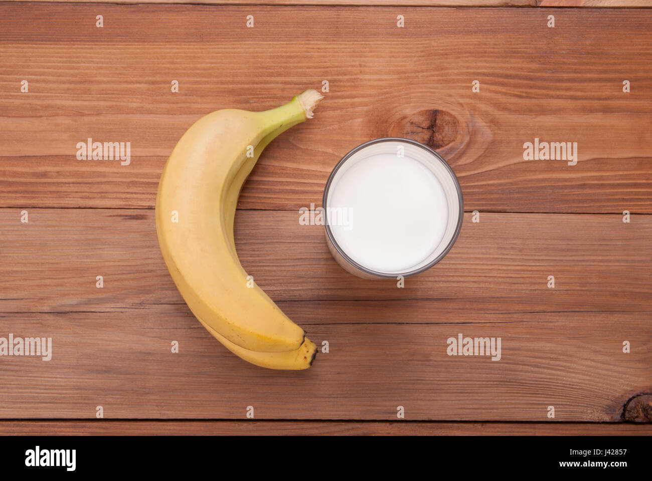 Glas Milch und Bananen auf einem hölzernen Hintergrund. Ansicht von oben. Stockfoto