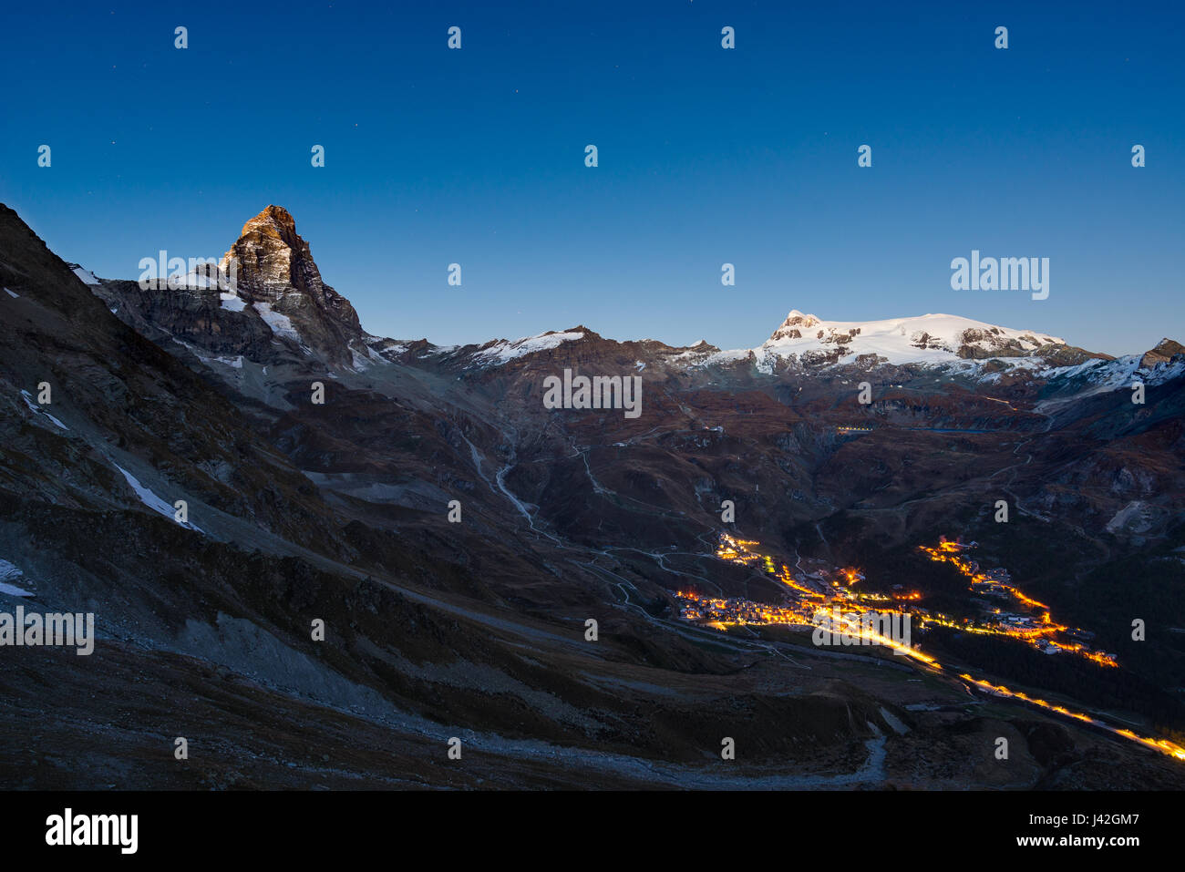 Luftaufnahme von Breuil Cervinia Dorf Leuchten in der Nacht, die berühmten Skigebiet im Aostatal, Italien. Wunderbaren Sternenhimmel über Matterhorn (Cervino) Stockfoto