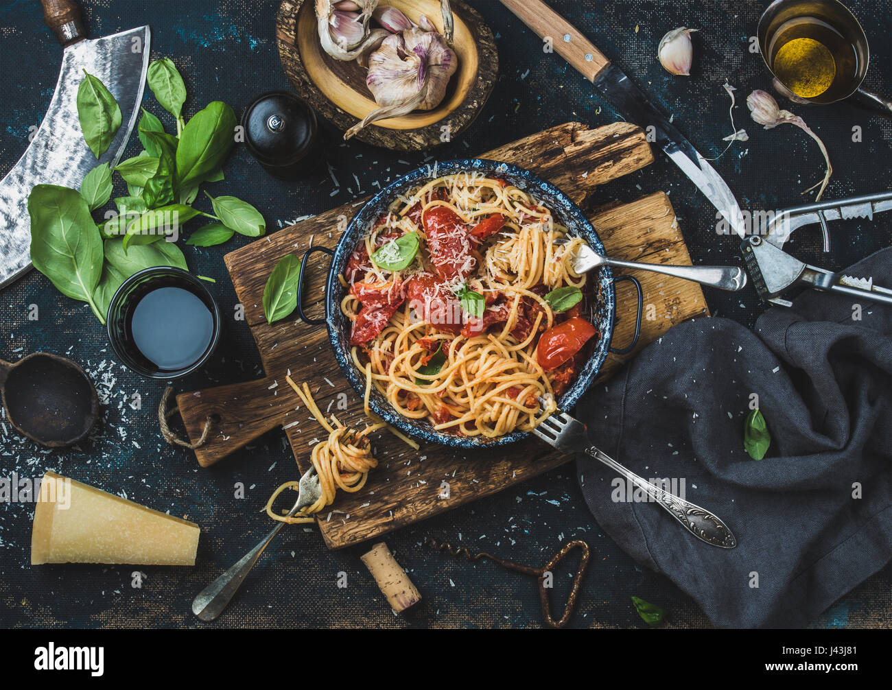 Spaghetti mit Tomaten und Basilikum und Zutaten für die Herstellung von Teigwaren Stockfoto
