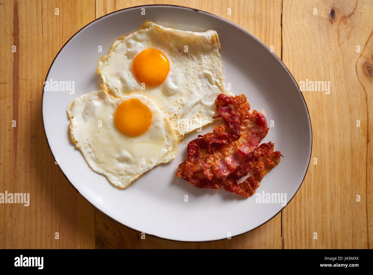 Frühstück Speck und Eiern über einfach auf Holztisch Stockfoto