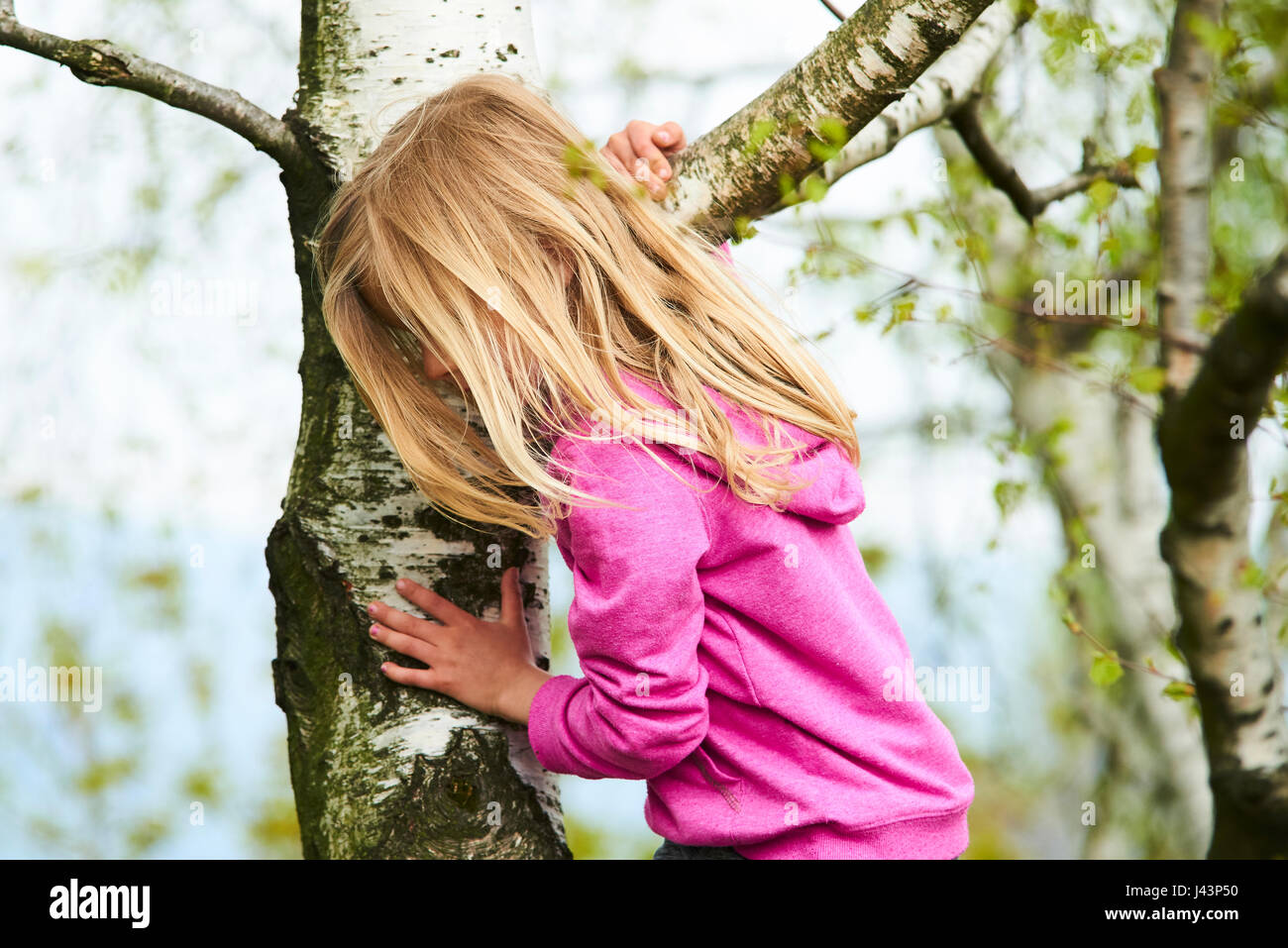 Kind blondes Mädchen Kletterbaum in einem Park im freien Stockfoto