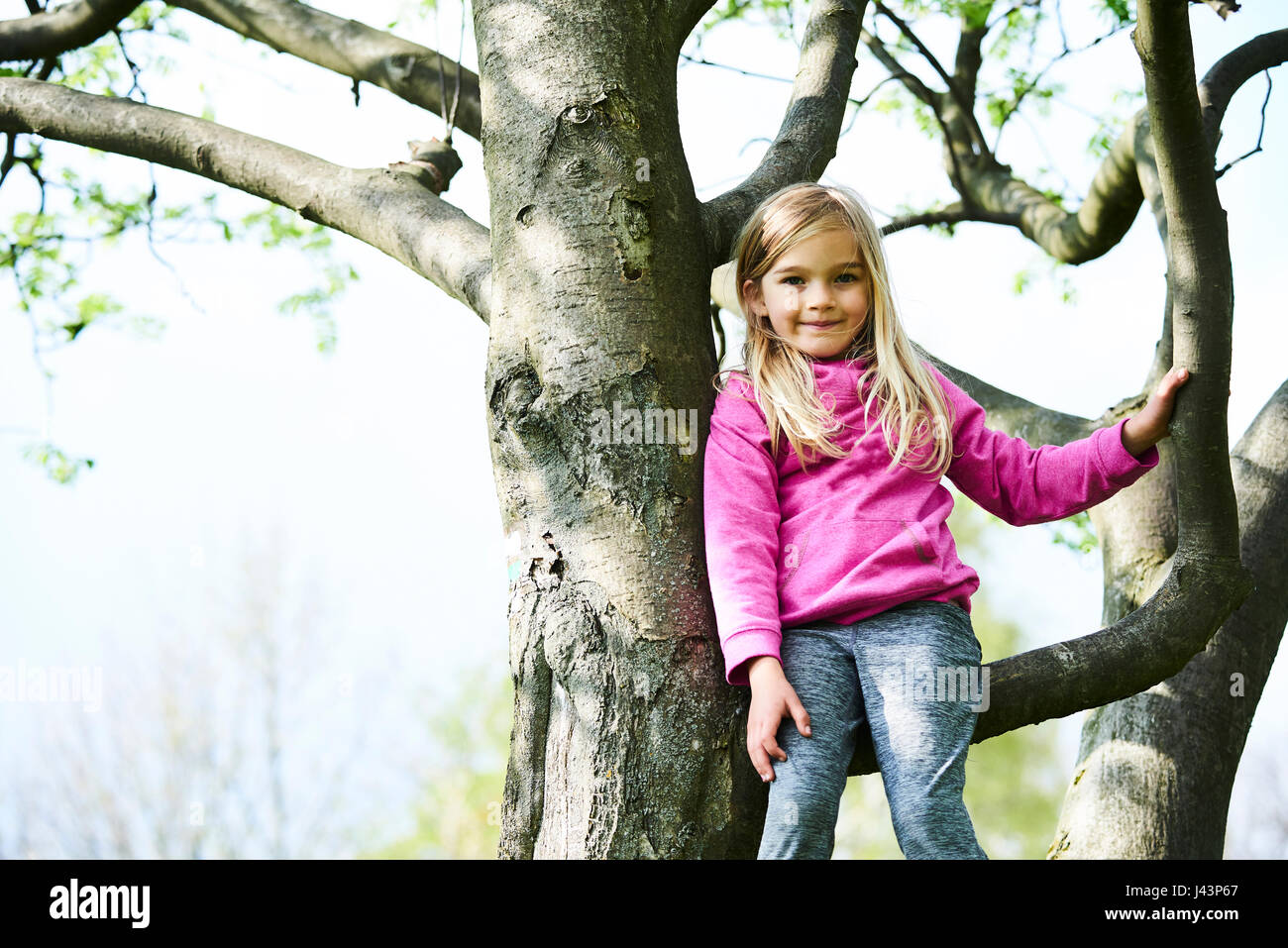 Kind blondes Mädchen Kletterbaum in einem Park im freien Stockfoto