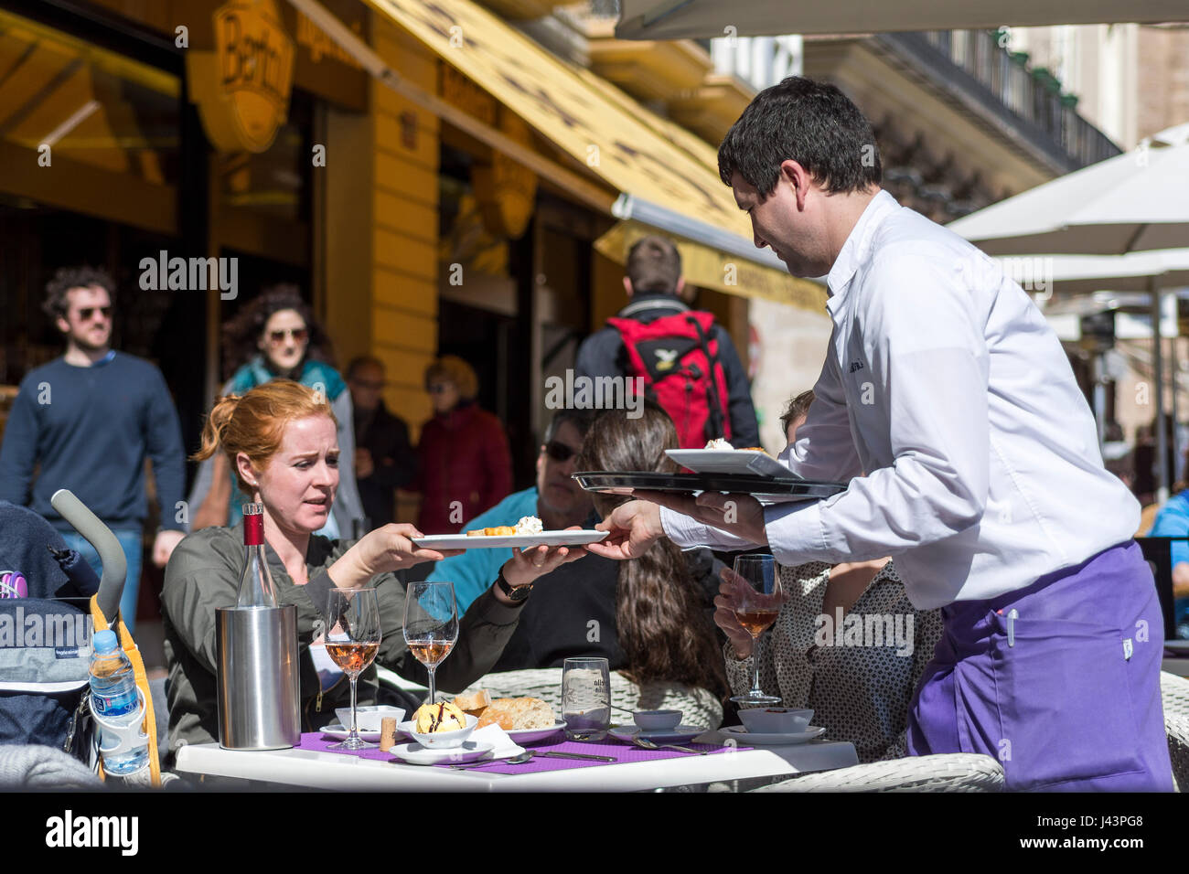 Kellner Teller ein Mittagessen, einem Frau zu Gast in einem Außen-Restaurant Stockfoto