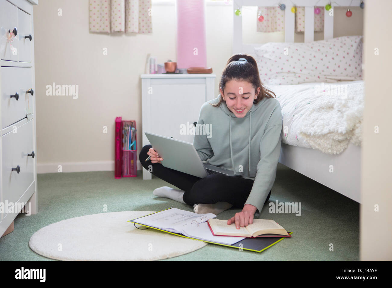 Junges Mädchen am Boden des Schlafzimmers Hausaufgaben auf Laptop Stockfoto