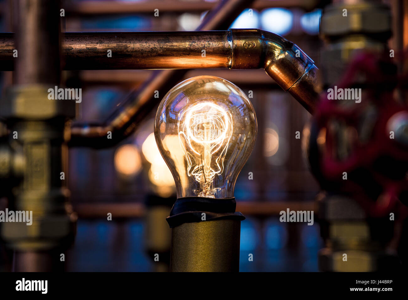 Weißglühende Glühlampe zwischen rostigen Rohren Stockfoto