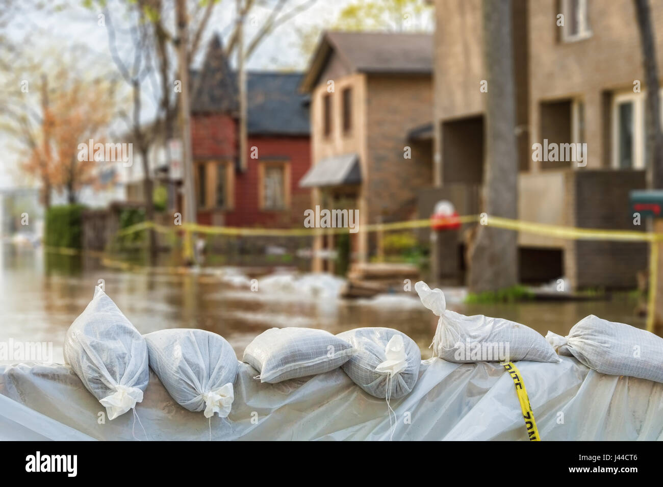 Schließen Sie Schuss von Hochwasser Schutz Sandsäcke mit überfluteten Häusern im Hintergrund Stockfoto