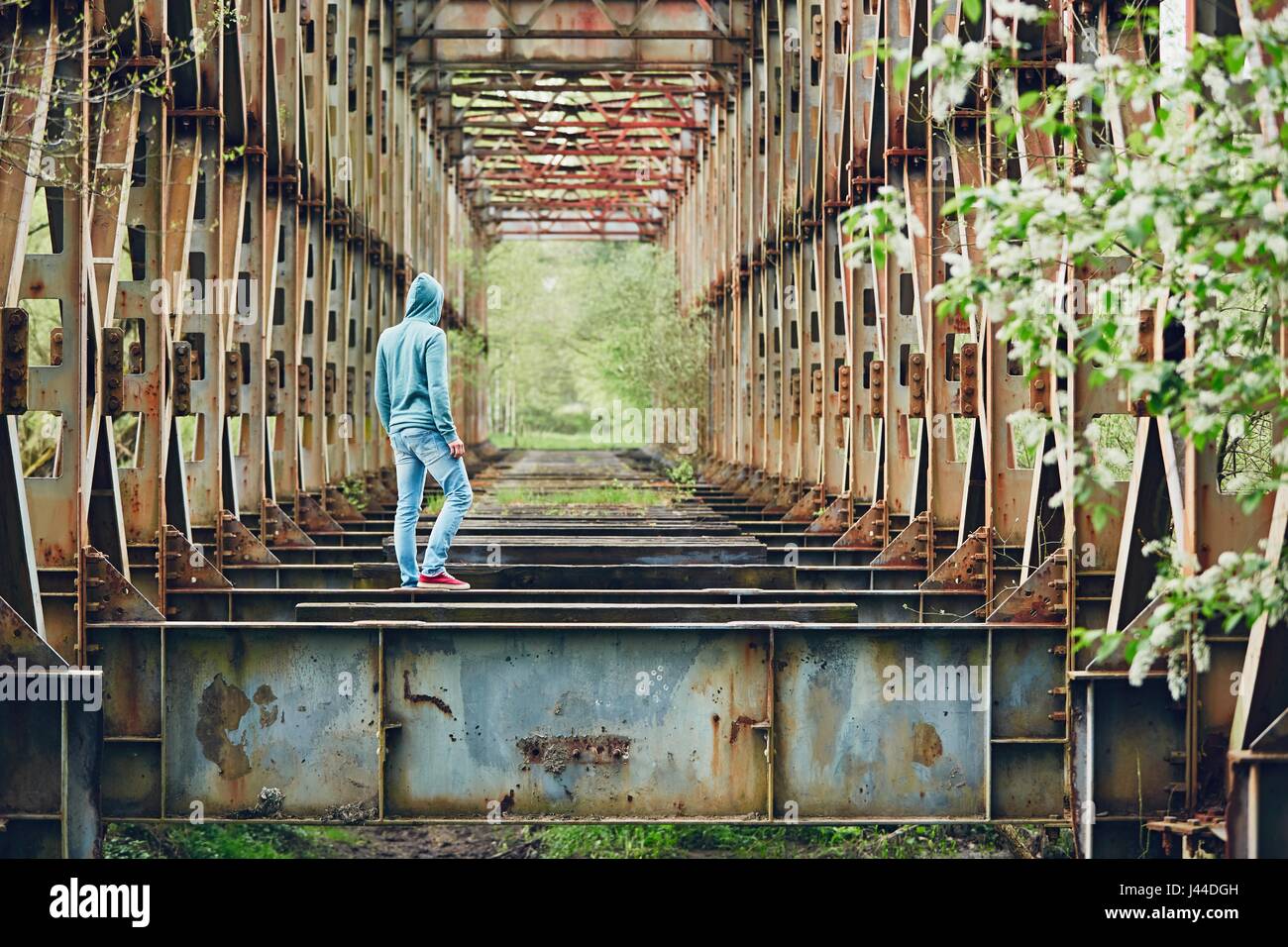 Trauriger Mann zu Fuß auf der verlassenen rostigen Brücke. Konzept für Traurigkeit, Einsamkeit und vieles mehr. Stockfoto