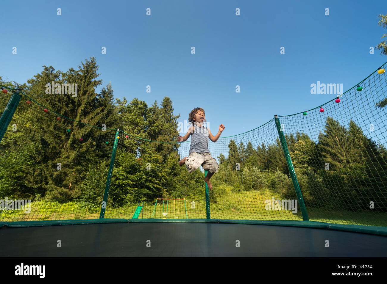 Süsser Boy genießt springen und hüpfen auf dem Trampolin Oudoors. Stockfoto