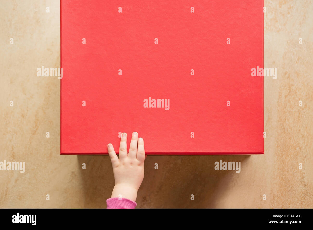 Niedliche Baby Hand auf einem roten Geschenk-Box Stockfoto