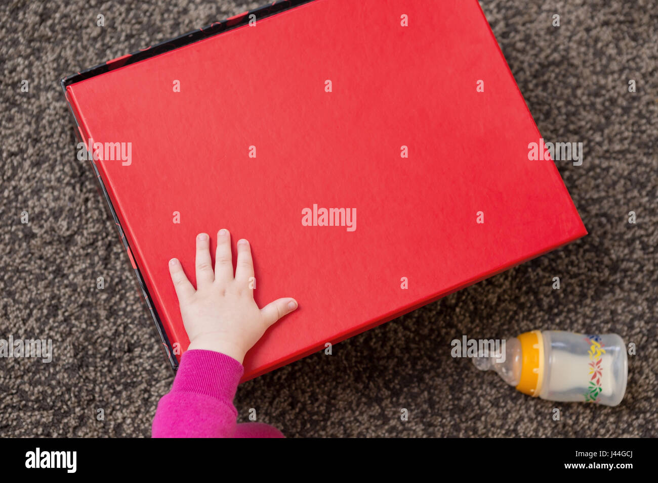 Niedliche Baby Hand auf einem roten Geschenk-Box Stockfoto