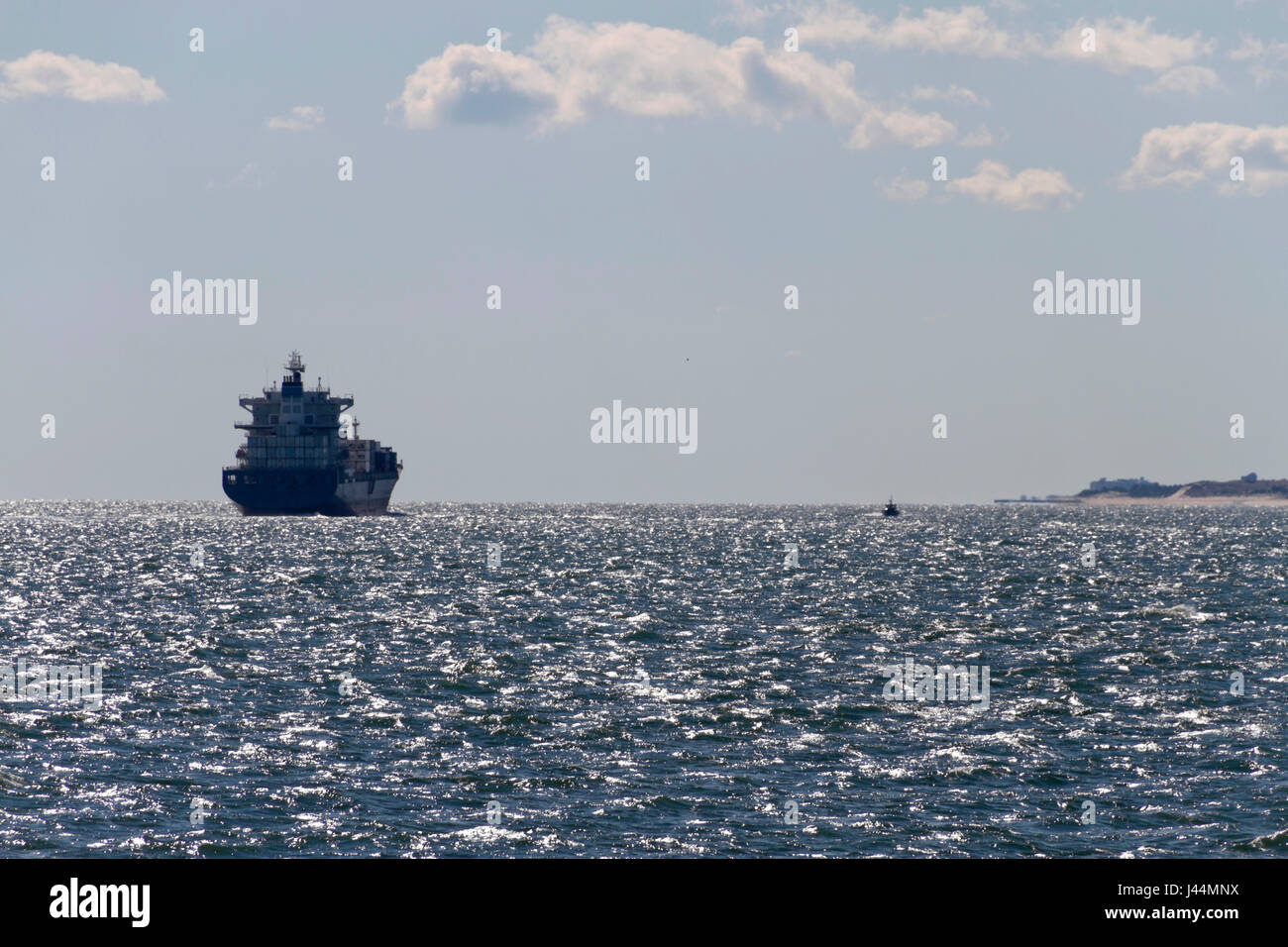 Ein großes Schiff erfüllt eine kleine Tug Boat auf der Chesapeake Bay ohr Land an einem sonnigen Tag Stockfoto