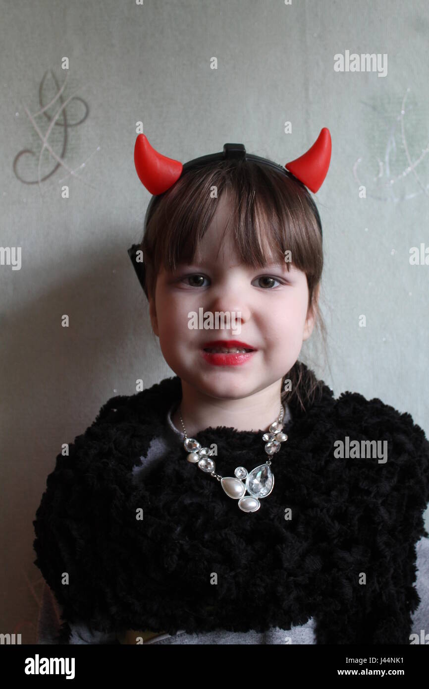 schöne dunkelhaarige Mädchen im Kostüm des Teufels mit roten Hörnern auf dem Kopf Geburtstagsparty Stockfoto
