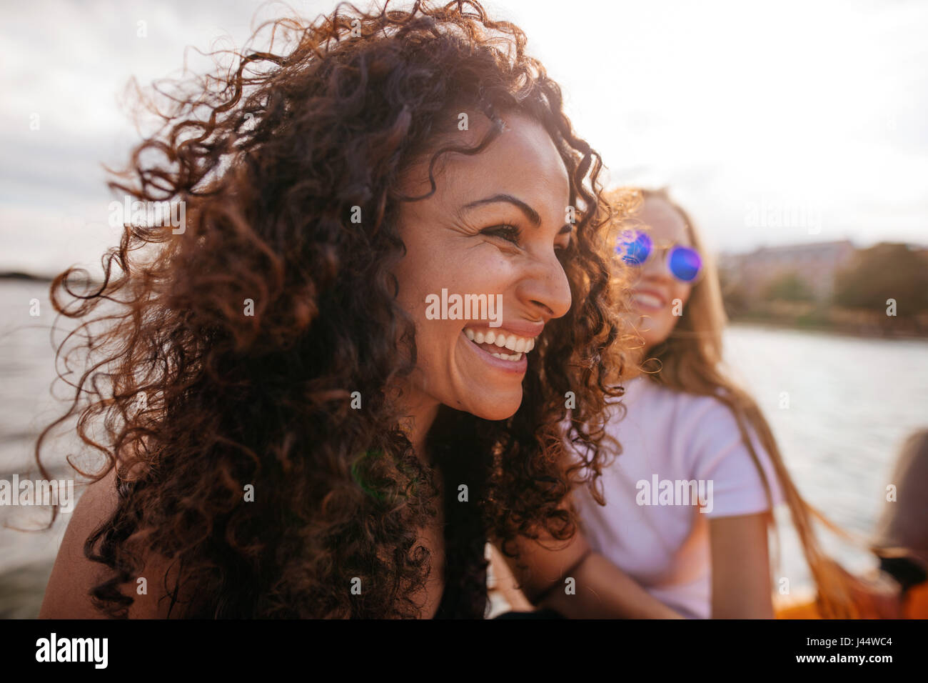 Schuss der fröhliche junge Frau im Freien mit Freundin im Hintergrund hautnah. Stockfoto