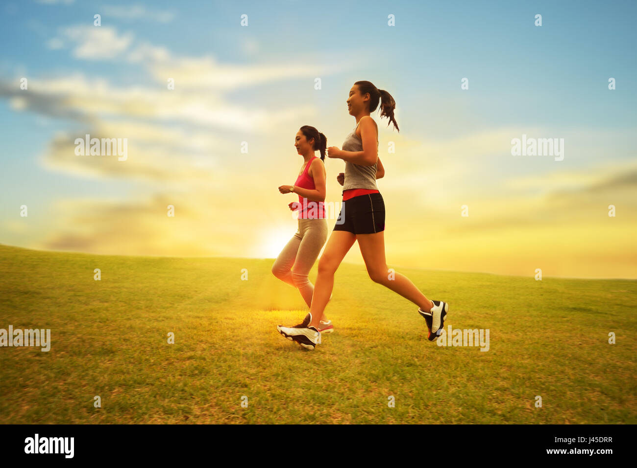 Zwei Mädchen laufen. Auf der Wiese neben der Sonne Stockfoto