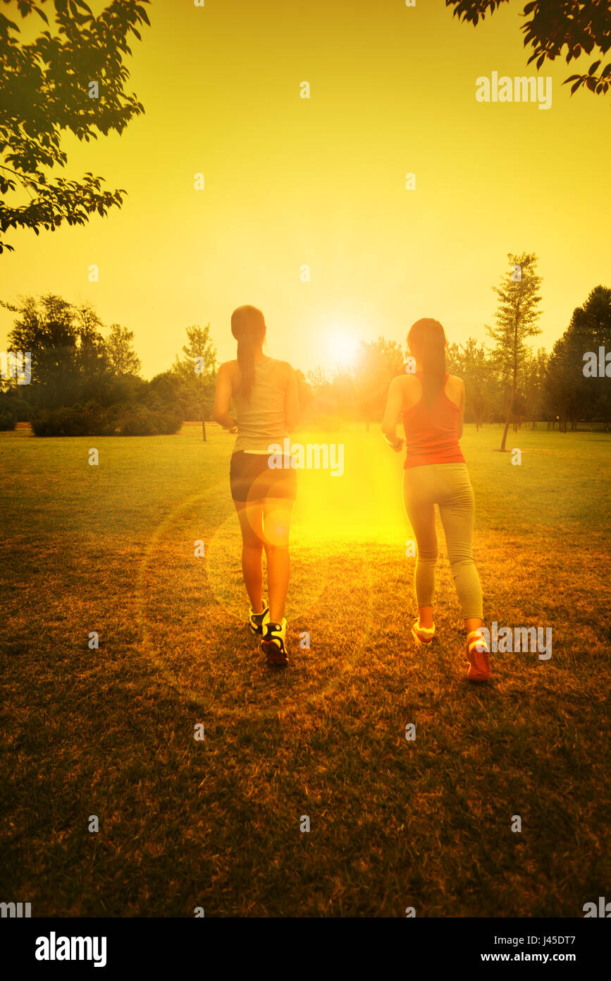 Zwei Mädchen im Park auf dem Rasen laufen. Rückansicht des Sonnenlicht am Morgen Stockfoto