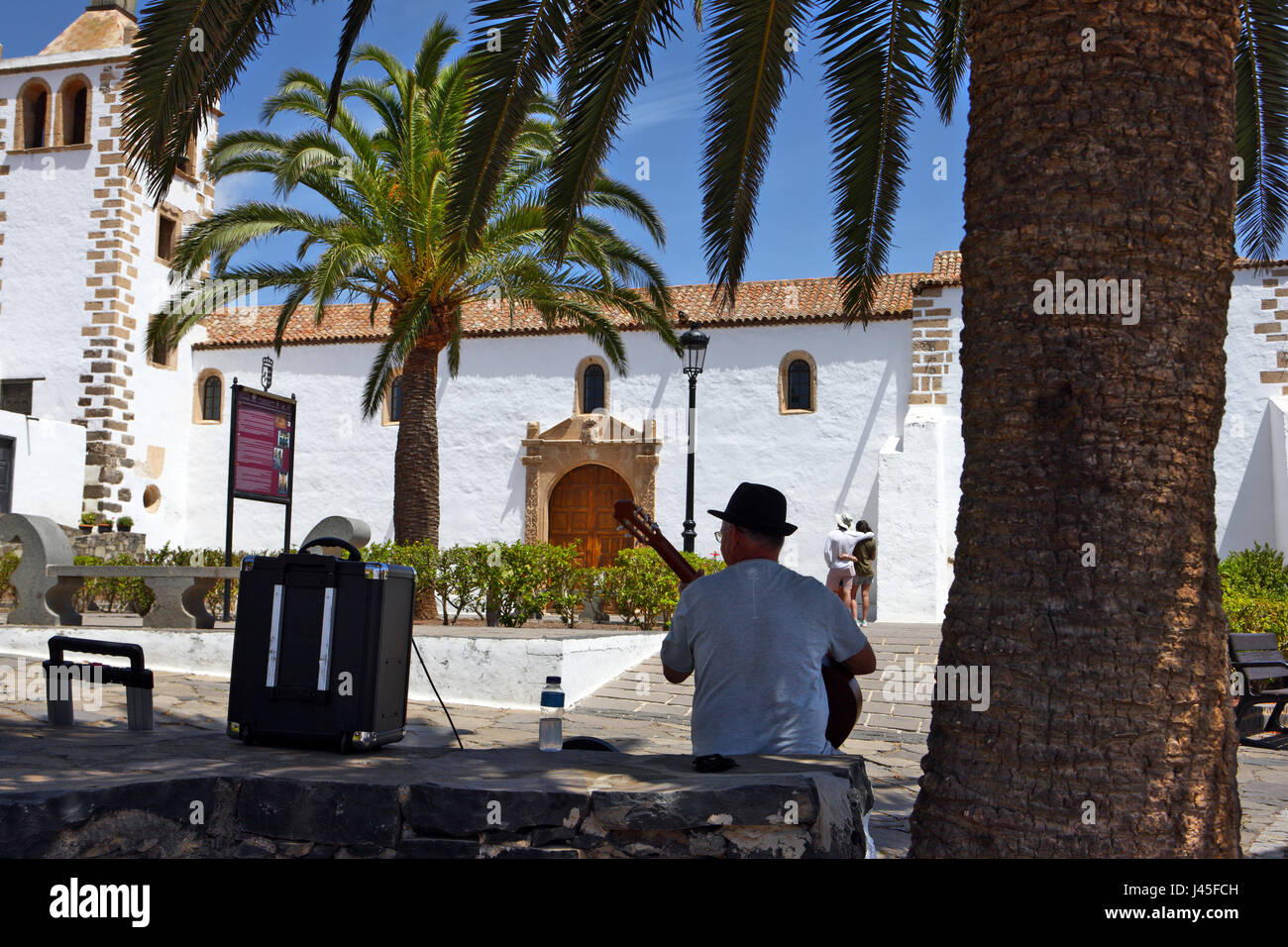 Mann, eine Gitarre zu spielen, im Schatten, gegenüber der Kirche Santa Maria de Betancuria auf der spanischen Insel Fuerteventura, Spanien Stockfoto