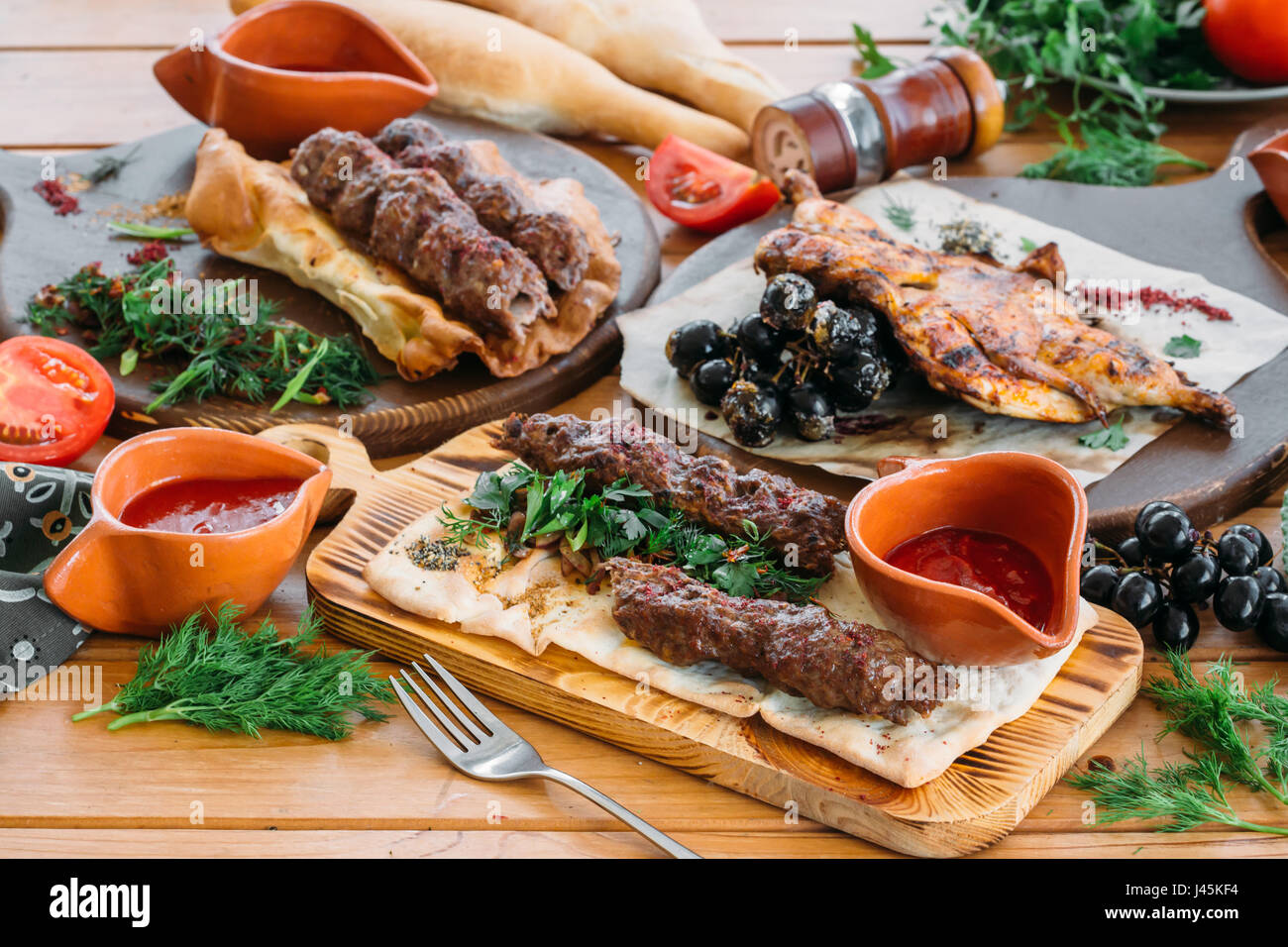 Hackfleisch / Faschiertes Lyulya Kebab mit frischem Gemüse und Saucen auf dem Serviertisch. Traditionelle georgische Abendessen Stockfoto