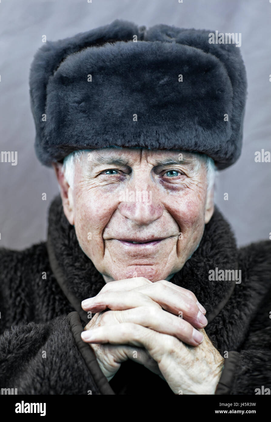 Alten kaukasischen Mann mit faltigen verwitterten Gesicht mit pulsierenden blauen Augen tragen eine Sowjet-Ära russische Militäruniform mit Biber Fell Wintermütze Stockfoto