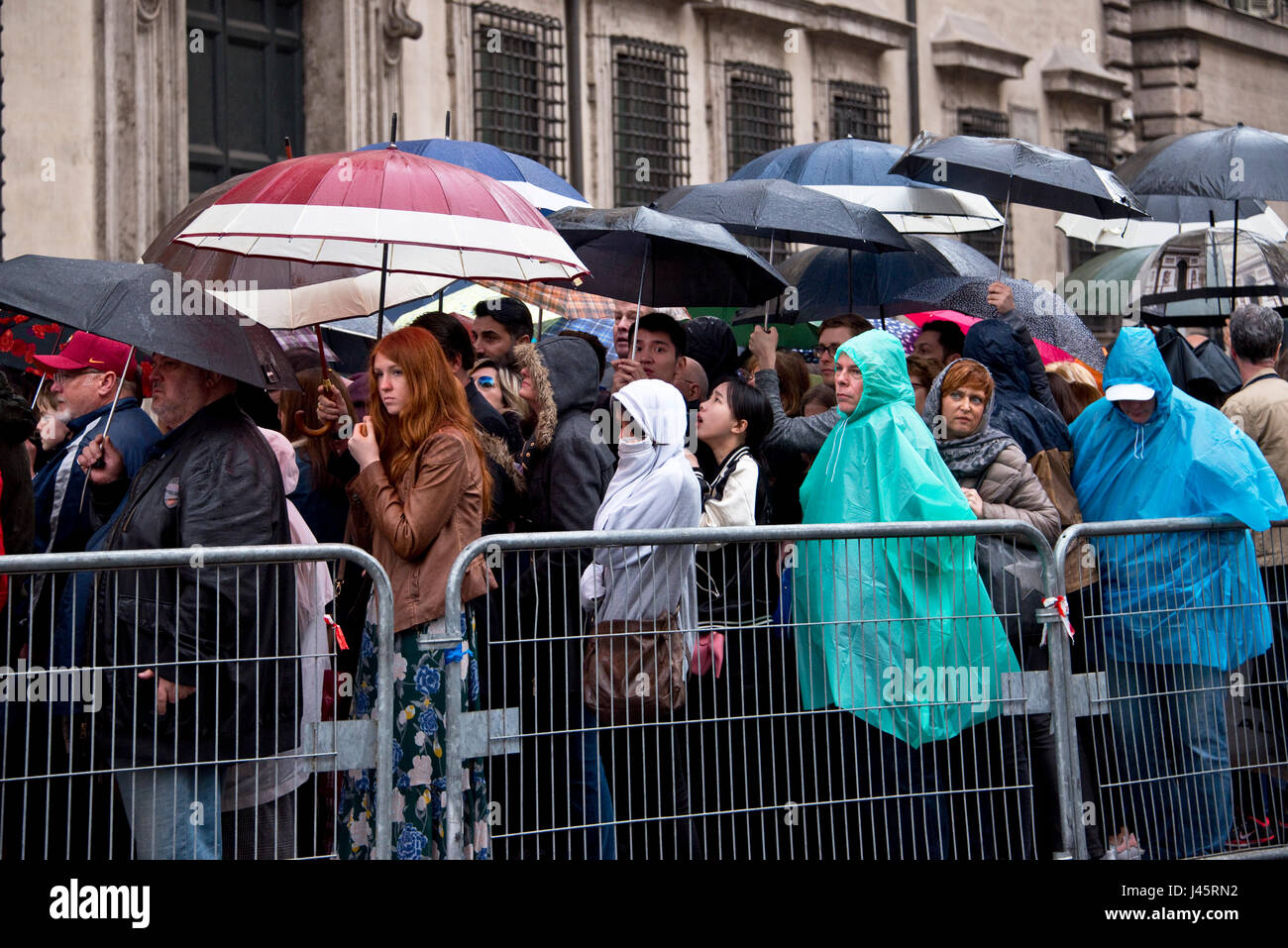 Menschen Sie Queing im Regen an einem verregneten Tag Elend in Rom mit vielen vielen Sonnenschirmen und Plastik Regenschutz. Stockfoto