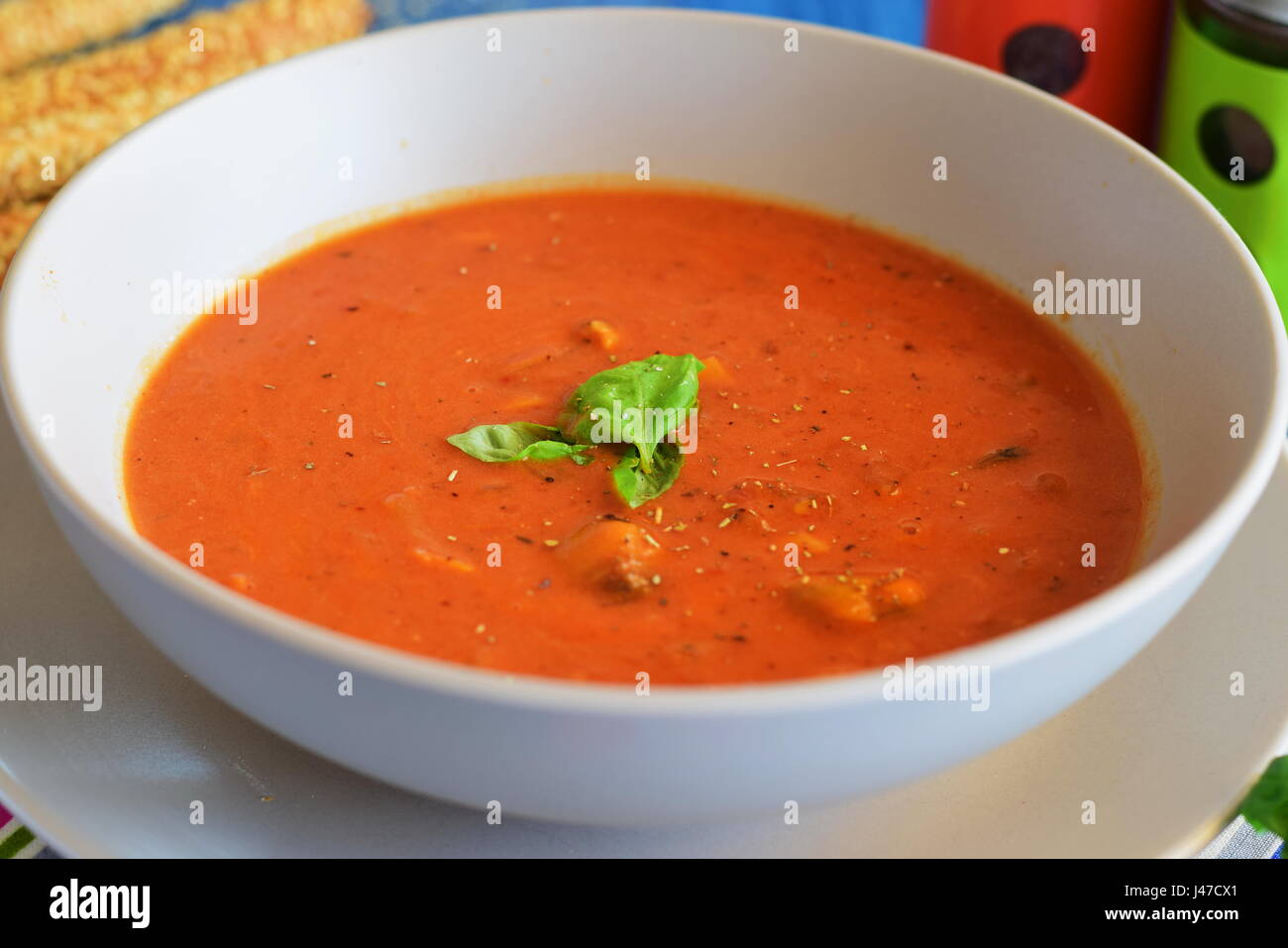 Tomatensuppe mit Muscheln in einer blauen Schüssel auf einem blauen Hintergrund mit Brot-sticks. Gesunde Ernährung-Konzept. Stockfoto