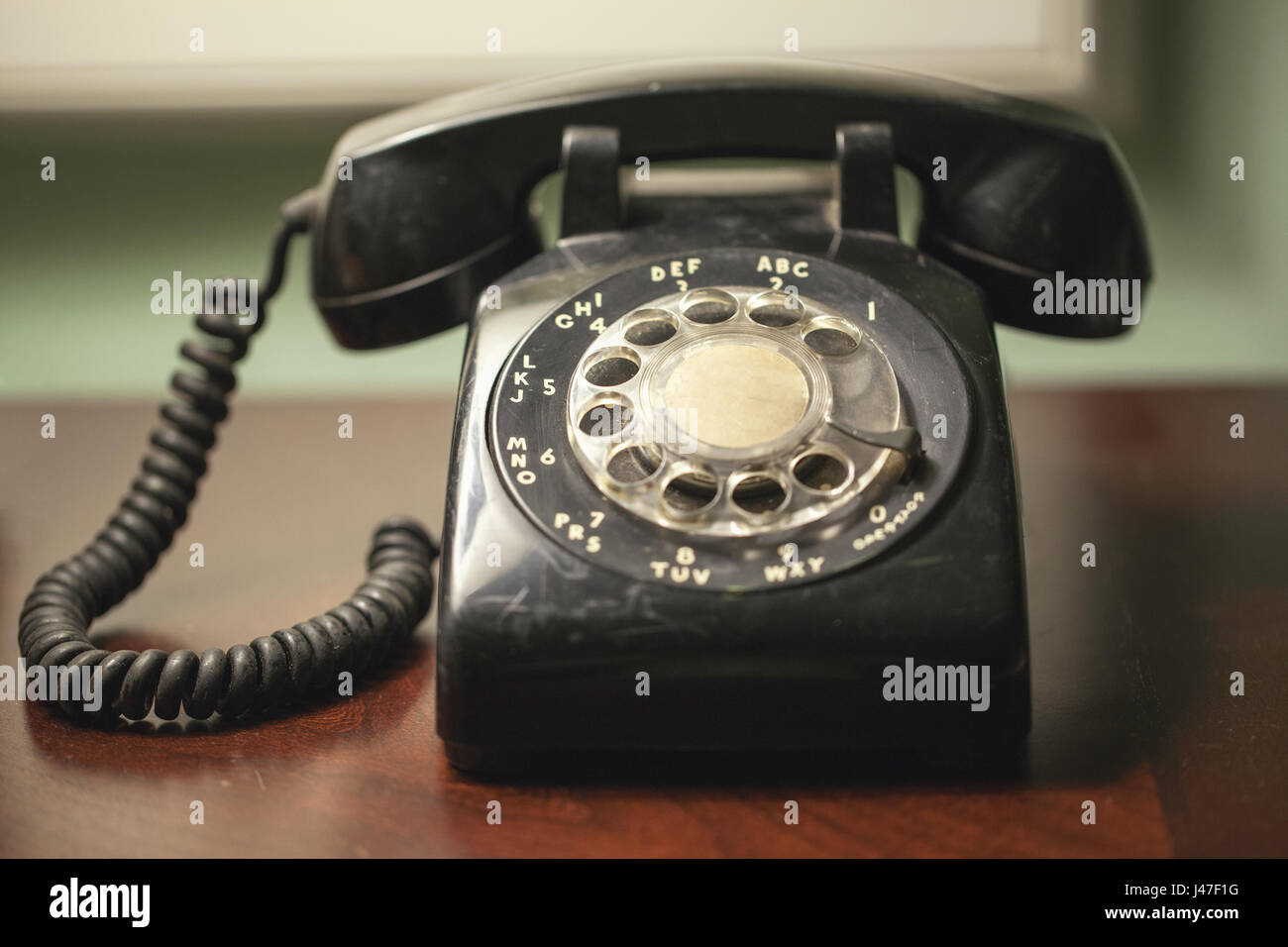 Antike Retro Vintage schwarz Rotary Telefon mit Spiralkabel auf einem Holz Schreibtisch Stockfoto