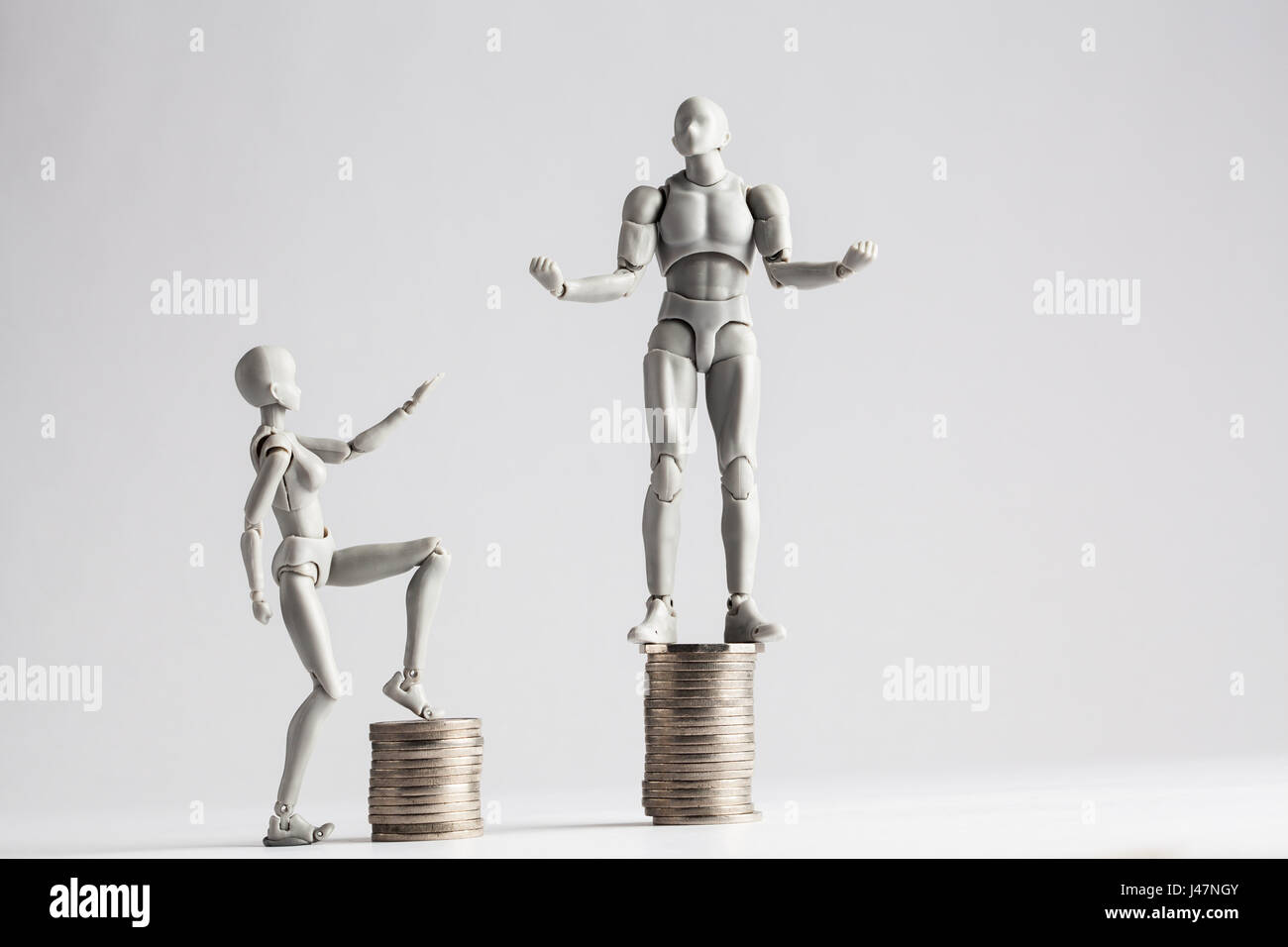 Einkommen Ungleichheit-Konzept mit realistischen männliche und weibliche Figurinen und Haufen von Münzen gezeigt. Weibliche Figur, die Hand in Richtung männlich Erweiterung Stockfoto