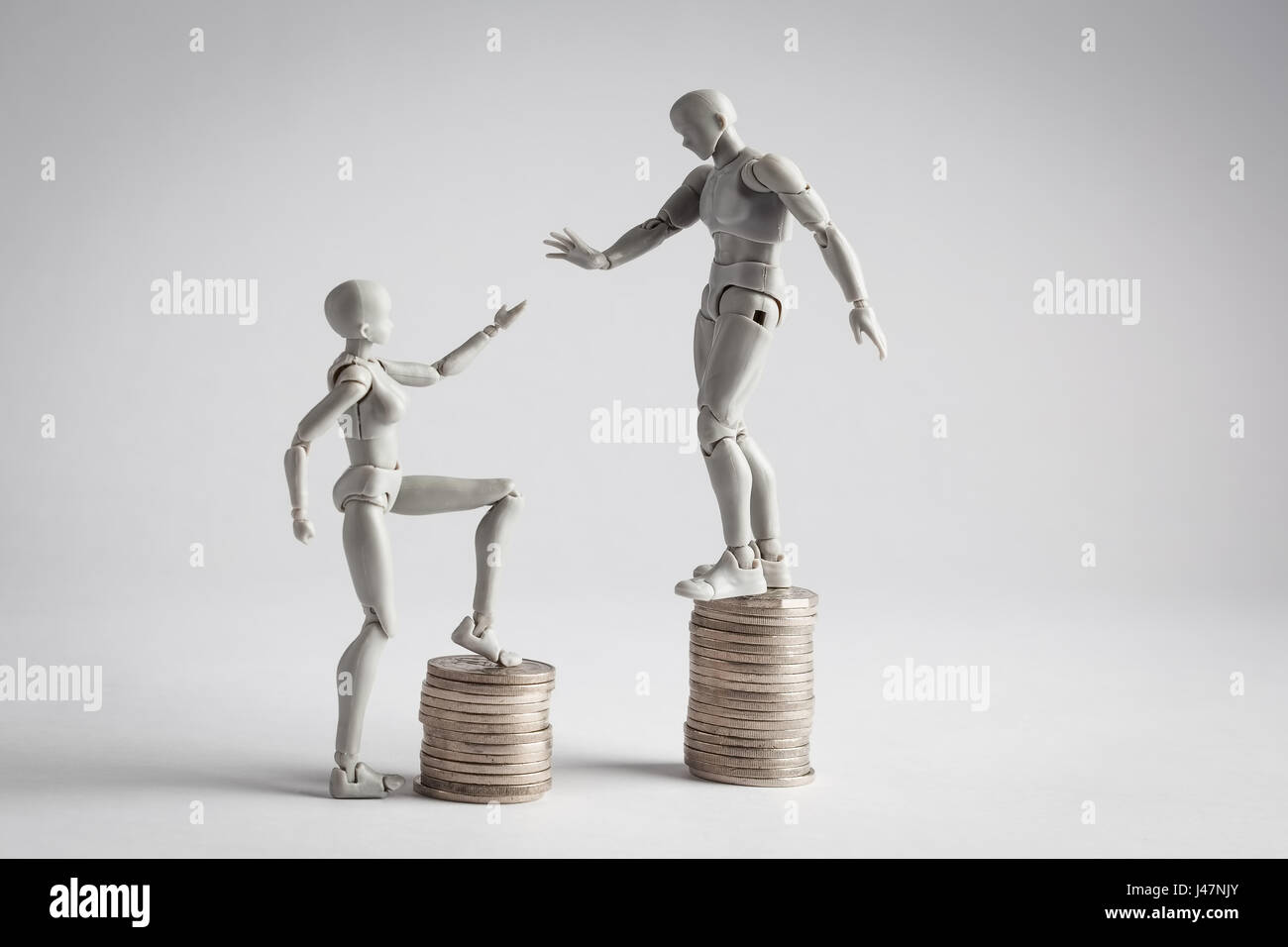 Einkommen Ungleichheit-Konzept mit realistischen männliche und weibliche Figurinen und Haufen von Münzen gezeigt. Weibliche Figur, die Hand in Richtung männlich Erweiterung Stockfoto