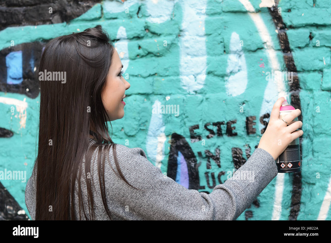 Portrait von junge Latin-Frau Zeichnung Graffiti mit Sprühfarbe auf Straße Wand. Im Freien. Städtebauliche Konzept. Stockfoto