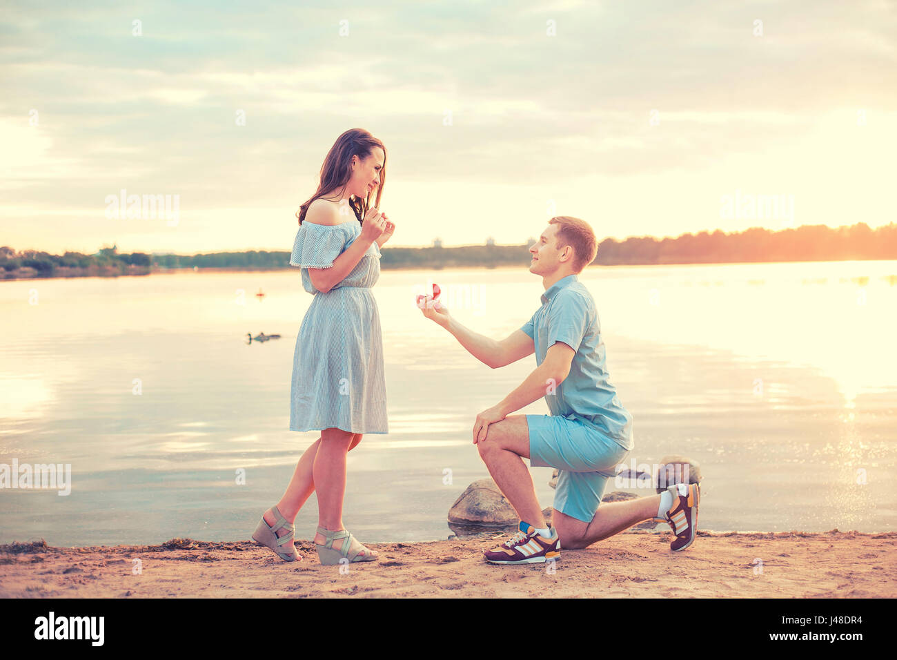 Heiratsantrag bei Sonnenuntergang. junger Mann macht einen Vorschlag der Verlobung mit seiner Freundin am Strand Stockfoto