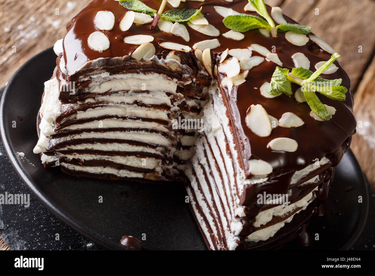 Delicious geschnittene Schokolade Crepes-Torte mit geschlagener Sahne und Mandeln Nahaufnahme auf einer Platte. horizontale Stockfoto