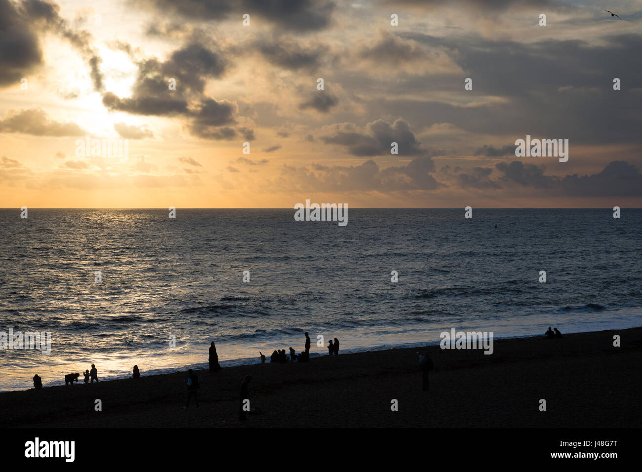 Brighton, UK. Strandbesucher Silhouette im späten Nachmittag Licht auf Brighton Beach. Stockfoto