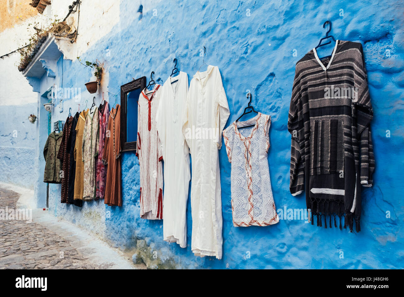 Traditionelle Kleidungsstücke aufgehängt, vor hellen blauen Hintergrund in Chefchaouen, Marokko, Afrika Stockfoto