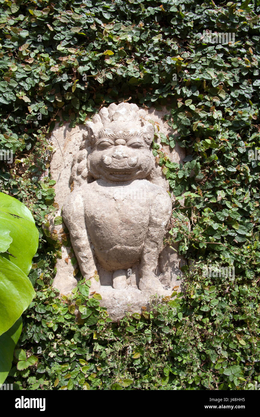 Eine kleine, steinerne Löwenstatue unter Blättern und Laub, Patan Museum Patan oder Lalitpur Kathmandu-Nepal Stockfoto