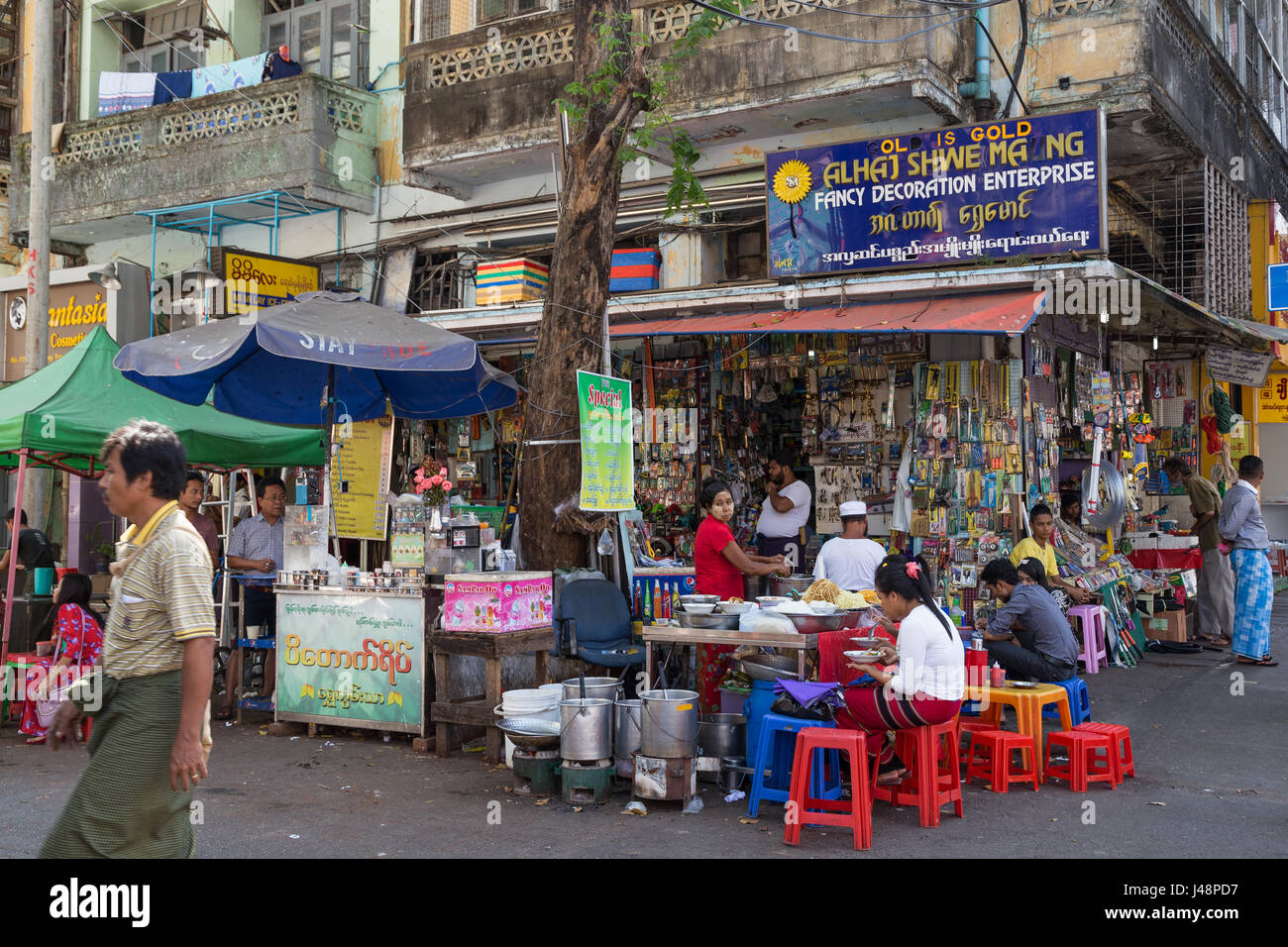 Menschen, Geschäfte und einfachen Stall Verkauf von Lebensmitteln an der Ecke von Maha Bandula Straße und 27th Street in Yangon (Rangoon), Myanmar (Burma). Stockfoto