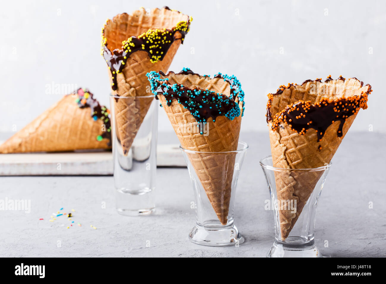 Hausgemachte Schokolade getauchte Eis Kegel mit Süßigkeiten Konfetti und  streut Dekorationen auf grauen Leuchttisch Stockfotografie - Alamy