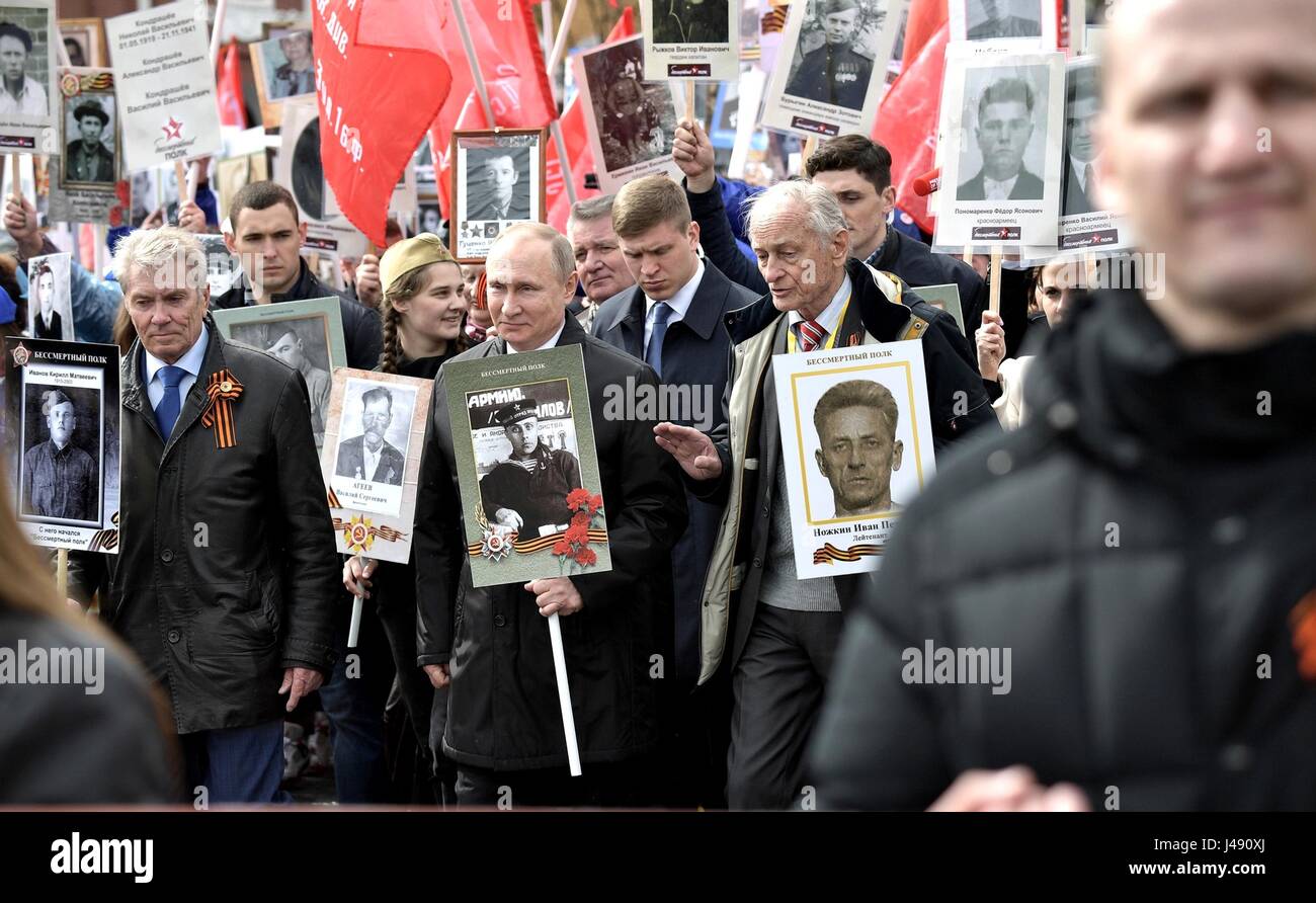 Russischen Präsidenten Vladimir Putin, Center, hält ein Porträt von seinem Kriegsveteran Vater Vladimir Spiridonovich Putin, als er marschiert neben ehemaligen sowjetischen Künstler, Vasily Lanovoya während der unsterblichen Regiment patriotischen März markiert die jährliche Feier der Tag des Sieges und der 72. Jahrestag des Endes des zweiten Weltkriegs auf dem Roten Platz 9. Mai 2017 in Moskau, Russland. Stockfoto