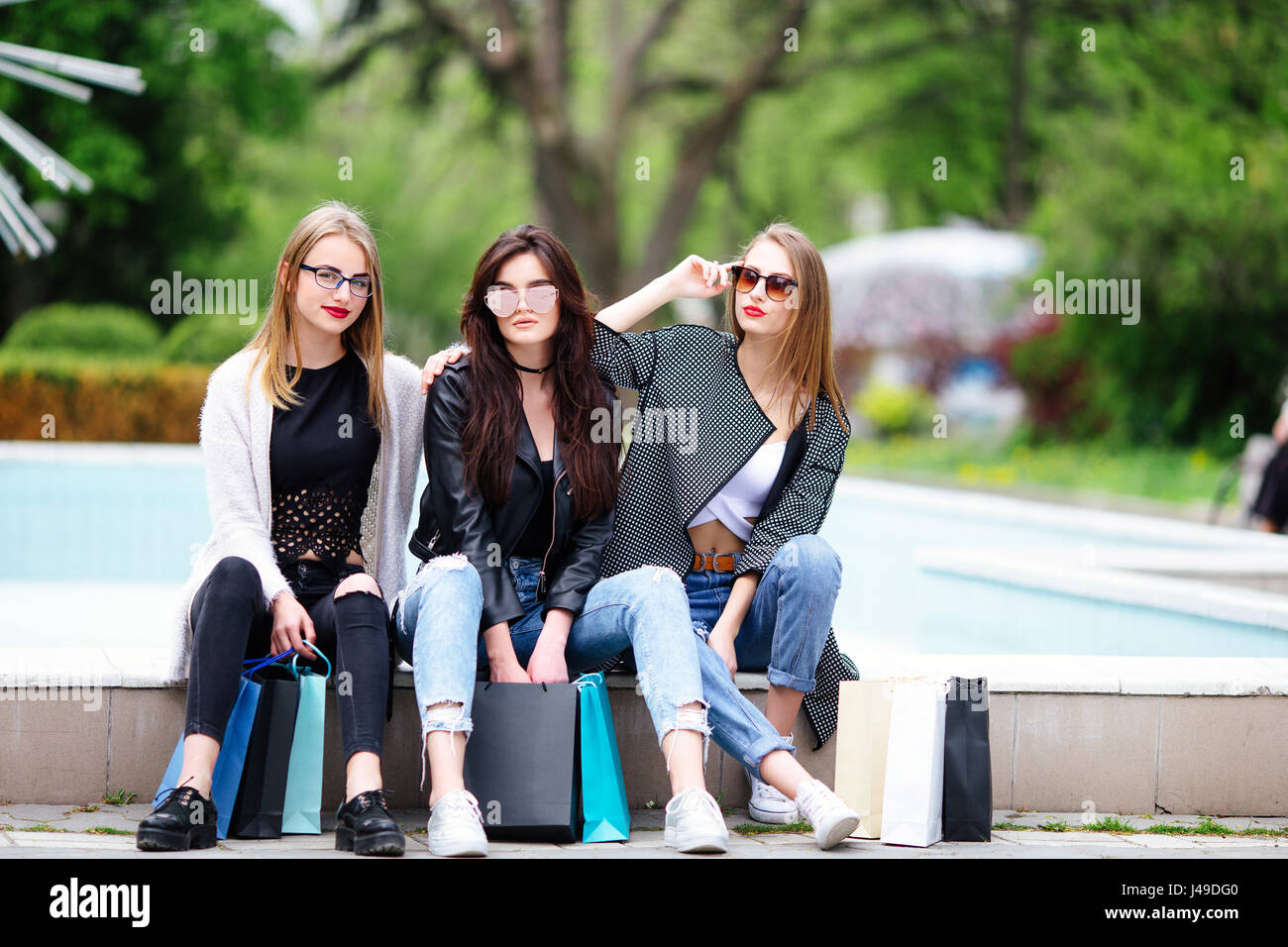 Drei Mädchen mit Einkaufstüten am Park Weichzeichnen Hintergrund Stockfoto