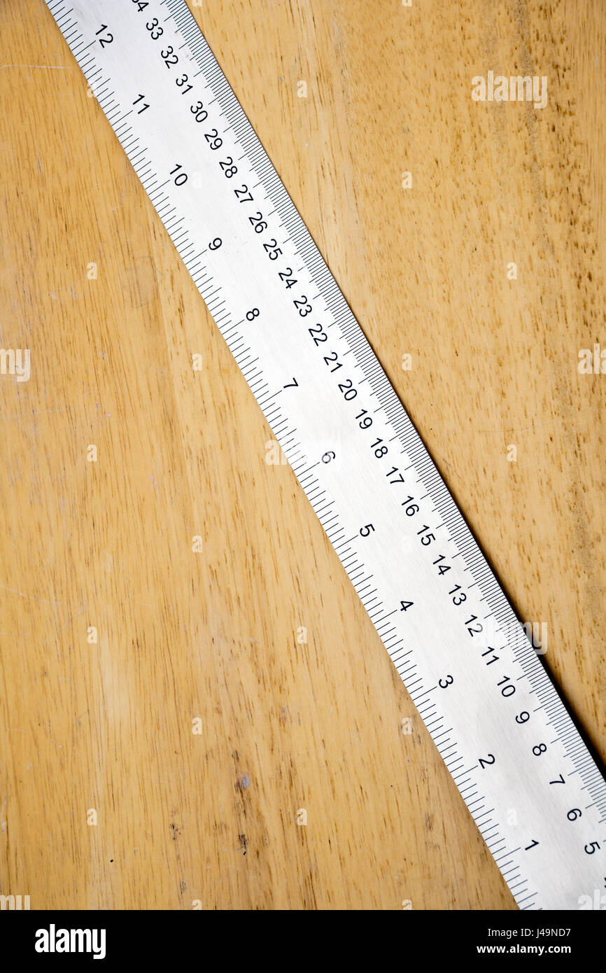 Eine glänzende neue Stahl-Regel auf Holz mit Textfreiraum Stockfoto