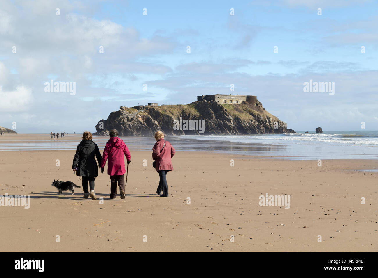 England, Wales, Tenby, Spaziergänger auf Tenby Beach in Richtung St Catherine's Island. Stockfoto